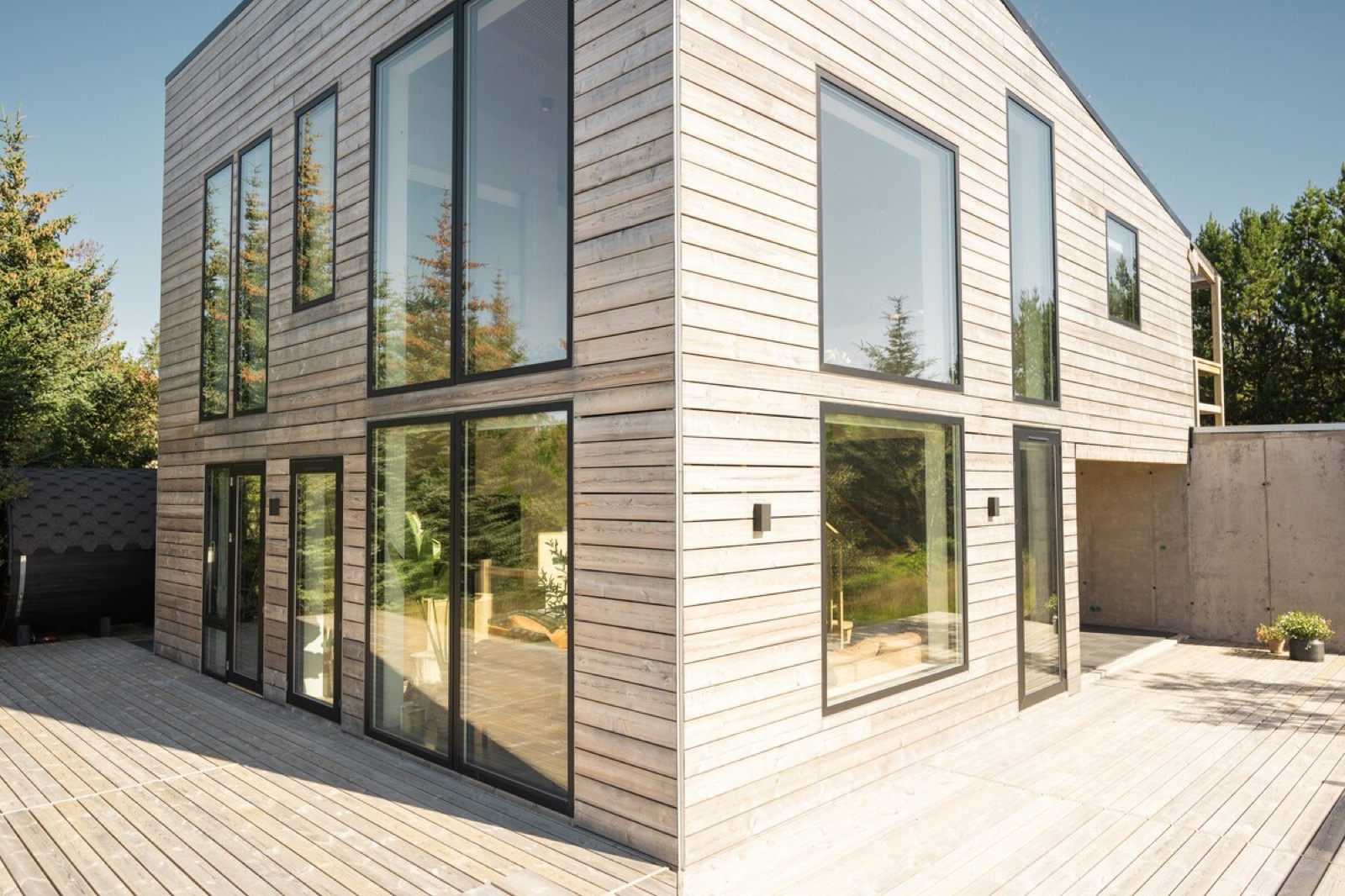 The villa’s glazed corner and deck, spruce woodland behind