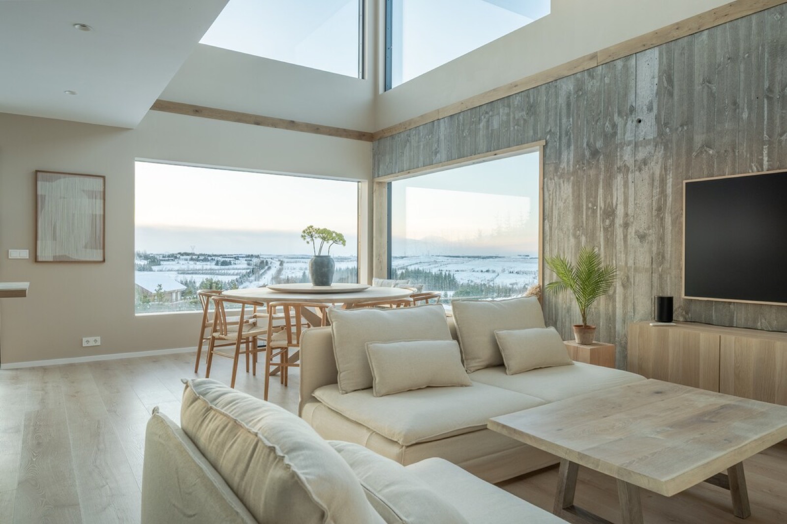 The double-height living room, pale linen sofas below a wall of glass