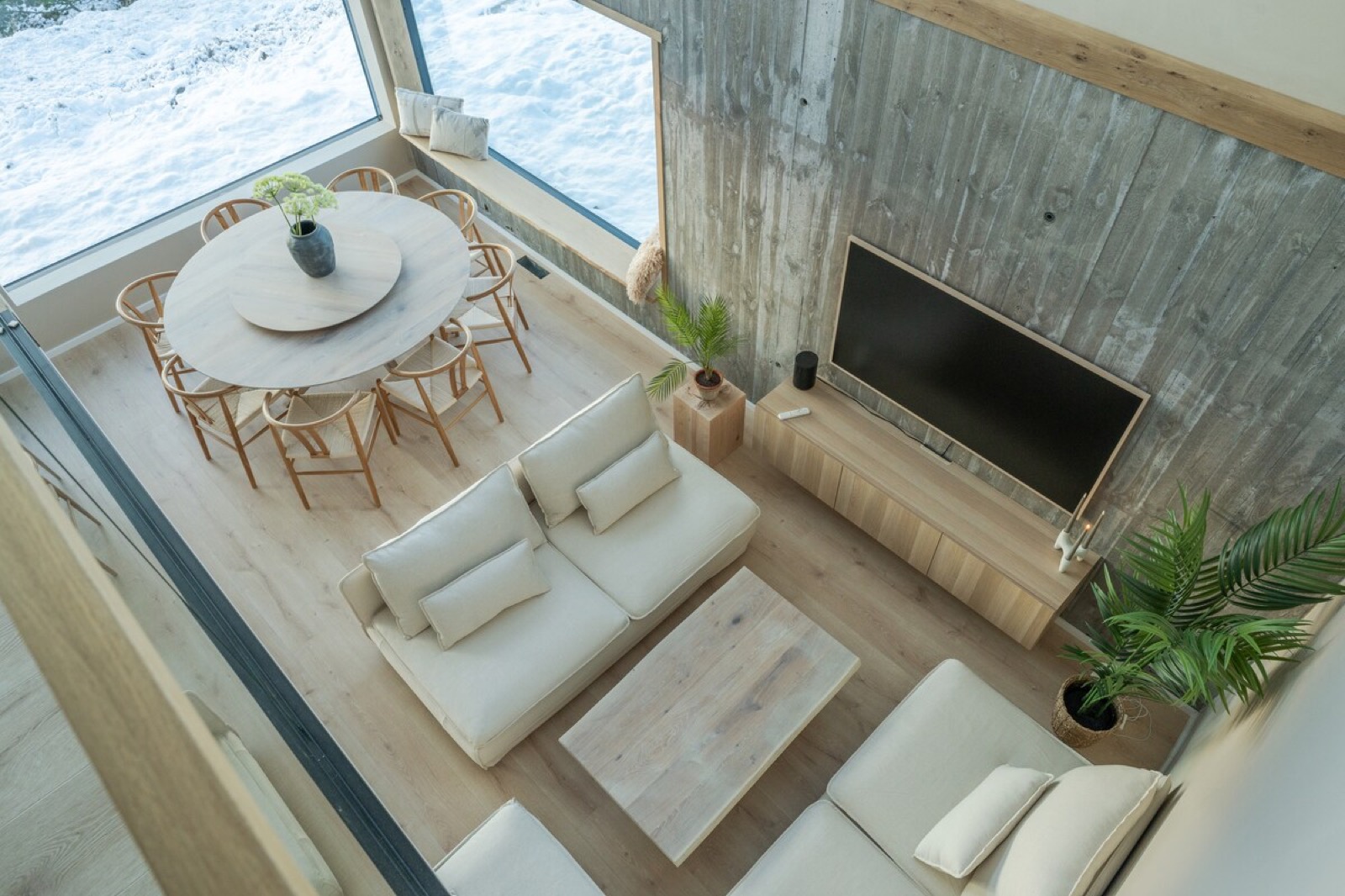 Board-formed concrete behind the dining table, snow-covered ground through the corner glazing