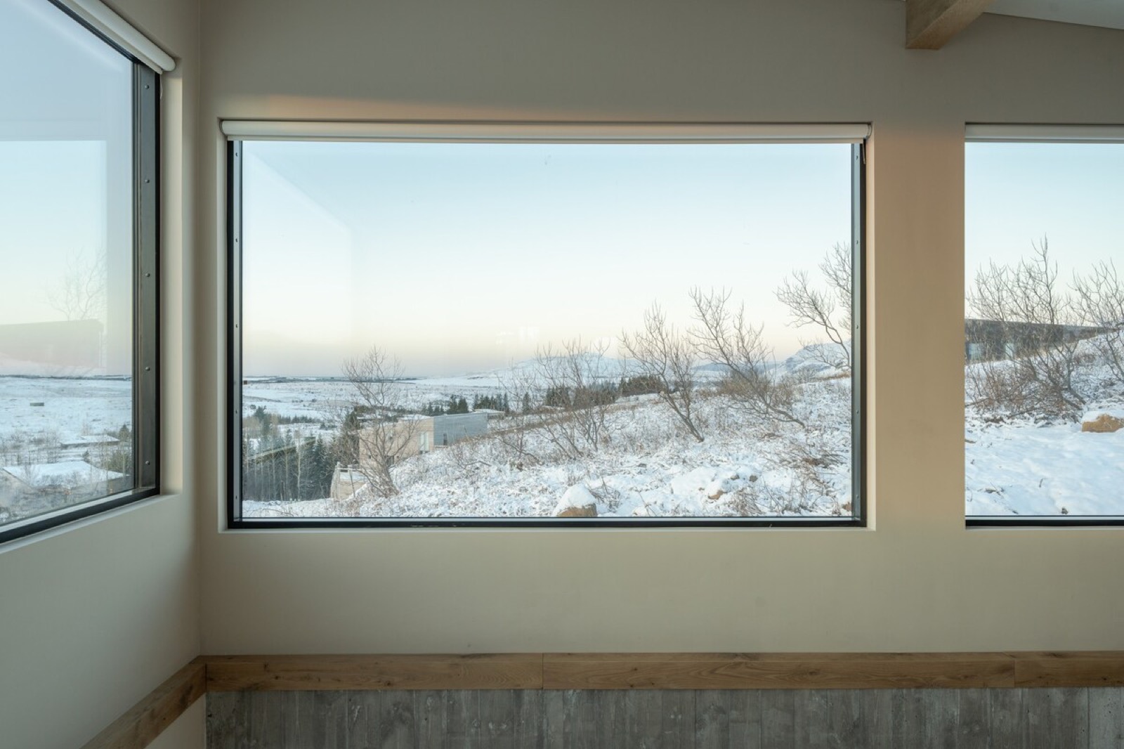 A long horizontal window laid across the snow-covered lowland, with a window on the wall either side of it